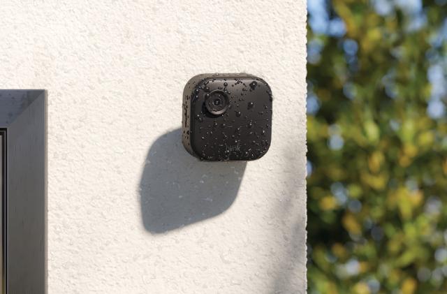 Image of Blink's Outdoor Camera 4, attached to a white rendered concrete wall covered in water droplets from a recent shower. 