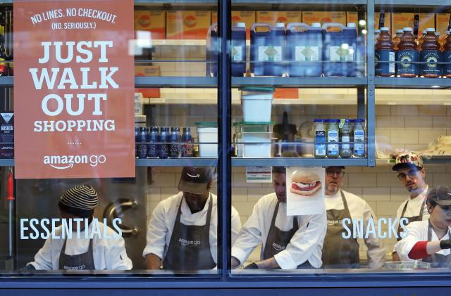 FILE - In this Jan. 22, 2018, file photo, workers as seen from a sidewalk window as they assemble sandwiches in an Amazon Go store in Seattle. A key executive behind Amazon Go, the online leader’s much heralded cashier-less grocery store, says she was surprised how many customers were hesitant to just walk out the store. (AP Photo/Elaine Thompson, File)